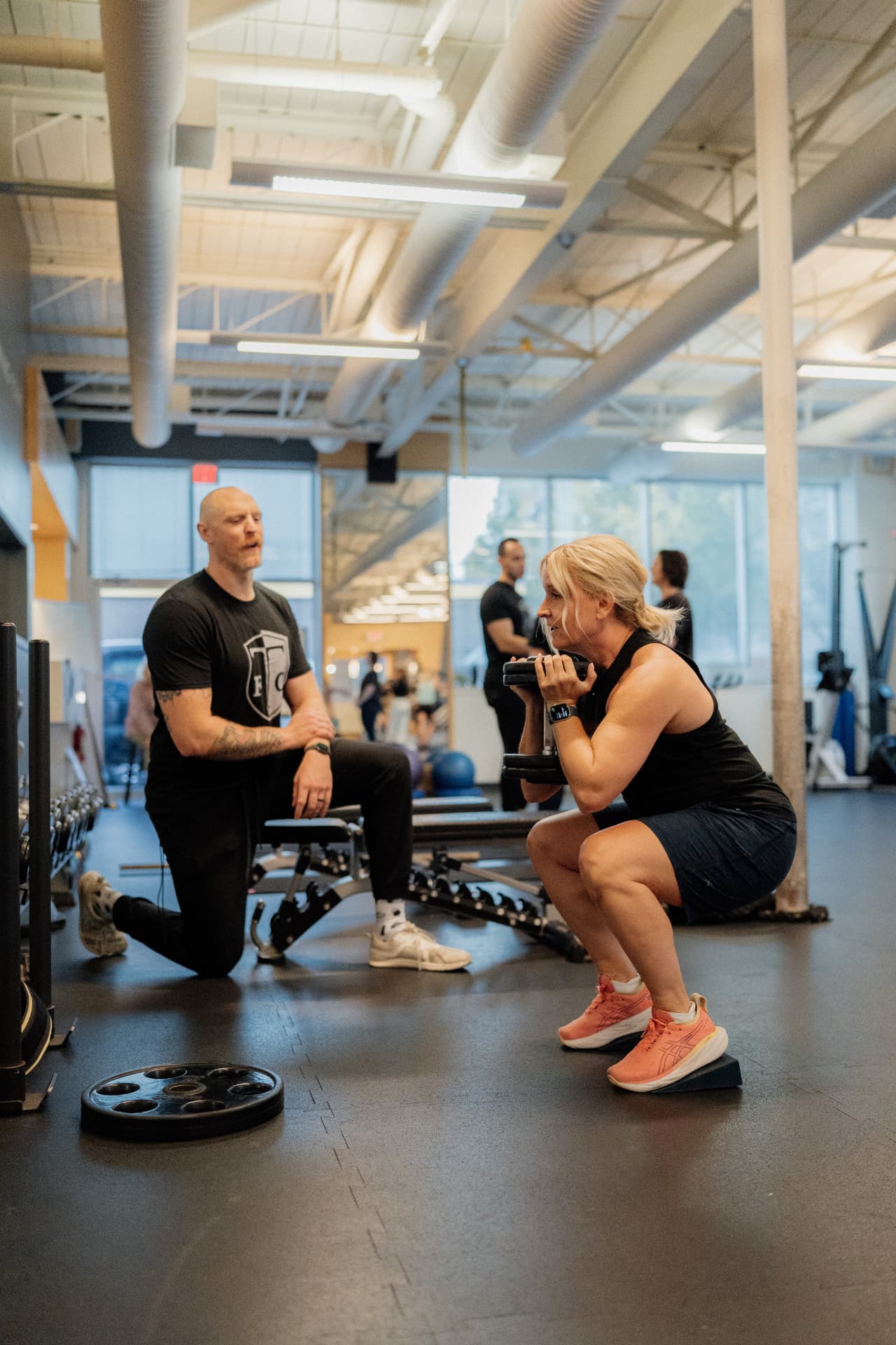 Coach guiding a goblet squat on a heel wedge